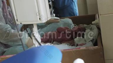 护士戴手套，浴衣用尿布覆盖新生儿在妇产医院哭泣的婴儿。 新生儿