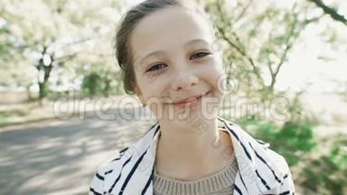 一个年轻微笑的女孩的特写肖像。 一个甜美的女孩看着相机笑。