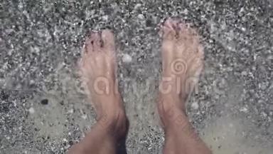 男子脚在海边的海滩上，高高的视野。 人站在海边，脚上沾满了水。 夏季和