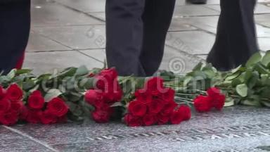在纪念碑前放<strong>红</strong>花。 庆祝伟大卫国战争的<strong>记忆</strong>。 我们只看到人的手和他们的腿。