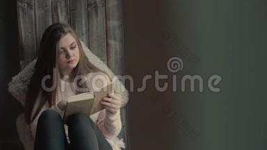 一位美丽的年轻女子坐在窗户上，看着一本<strong>书翻页</strong>