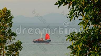 日落时分，一艘中国传统的<strong>红帆船</strong>沿着大海漂浮