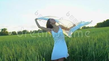 美丽的女孩，戴着围巾，随风飞翔，日落时在麦田里奔跑。 自由健康幸福观念