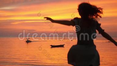 美丽的年轻女孩<strong>跑到</strong>水中，在热带海滩日落的背景下旋转。 慢动作