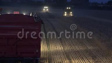 卡车站在接茬机和收割机上，灯光在夜间培育谷物玉米田。 4K