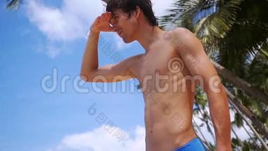 站在海滩上享受假期阳光明媚的一天的年轻英<strong>俊男</strong>子的视线从远处望去