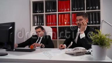 两个无聊的员工用电脑桌面在工作场所的桌子上玩小球。