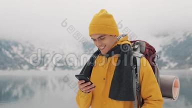 年轻的旅行者在徒步冬<strong>季</strong>旅行中使用智能<strong>手机</strong>。 白雪模糊的山角和湖。 旅行和