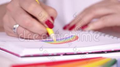 彩虹。 绘图过程。 我们画彩虹。 红色指甲的女人在白纸上画了一道明亮的彩虹。