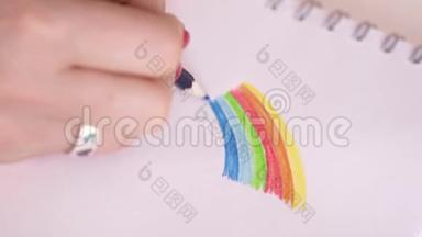 彩虹。 那个女人画了一支彩虹色铅笔。 红色指甲的女人在白纸上画了一道明亮的彩虹
