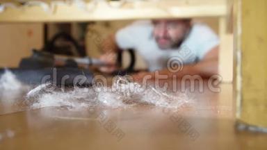 男人用吸尘器清洁床底下的地板