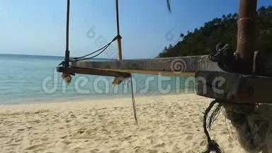 一个木制的秋千座椅挂在海边的椰树上，海滩干净，天空湛蓝。慢动作。1920x1080个