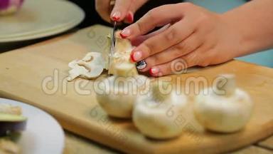 一个女人用一把刀在木板上把<strong>香瓜</strong>蘑菇切成薄片。