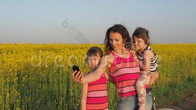 有孩子的快乐母亲在大自然中被拍摄。 家庭在本质上是自我的。 有孩子的女人在黄色的田野里