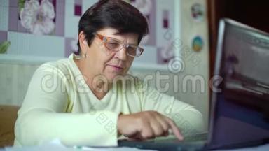 戴眼镜的老年妇女检查家里笔记本电脑的日常开支