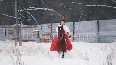 穿着红色连衣裙的漂亮的黑发年轻姑娘在冬天的雪地里骑着马飞驰
