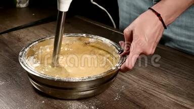 厨房里的一个糕点女孩在一个金属碗里特写，用搅拌机敲打面团做海绵蛋糕。 家庭烹饪
