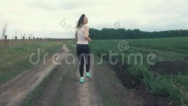 快乐的运动女孩在田间的道路上奔跑。 户外健身。 用安定剂射击