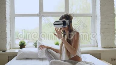 年轻开朗的女人戴着虚拟现实耳机，坐在家里的床上玩360VR电子游戏