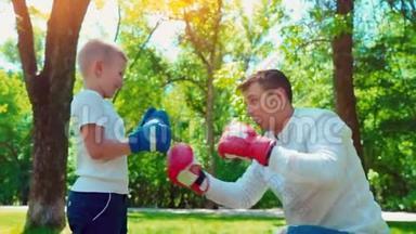 父亲和儿子戴着拳击手套在房子附近的草坪上打拳击