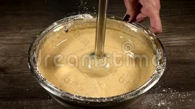 厨房里的一个糕点女孩在一个金属碗里特写，用搅拌机敲打面团做海绵蛋糕。 家庭烹饪