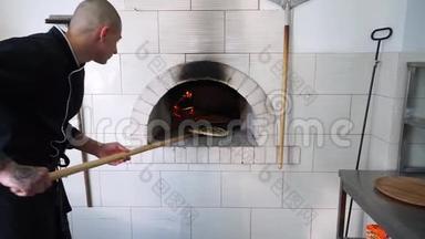 一个年轻的披萨师傅在餐馆的厨房里做披萨。厨师把比萨饼放在热烤箱里，然后把它翻过来