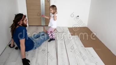 爸爸和女儿正在公寓里修理。 层压板铺设
