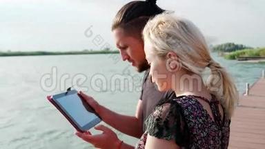 在湖边使用平板电脑的男孩和女孩在湖边使用平板电脑，ipad