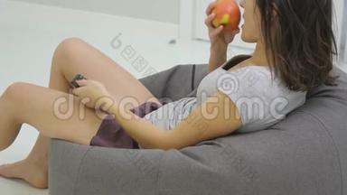 年轻的女人在客厅里看电视，吃苹果。 近点