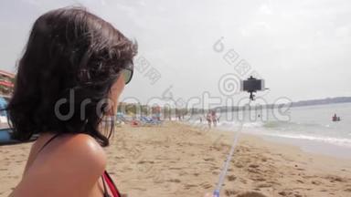 女孩用自拍棒在海边拍照