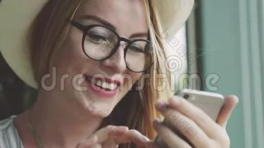 女孩在手机上和朋友聊天。 女人在咖啡馆的智能手机上写按摩，微笑。