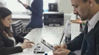 商务人士正在办公室里使用平板电脑和笔记本电脑