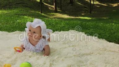 公园里一个很小很漂亮的女孩在床单上玩耍。