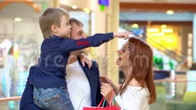 <strong>父母</strong>在贸易商场和儿子说话。 这家人在购物中心为圣诞节买东西。 快乐的<strong>父母</strong>