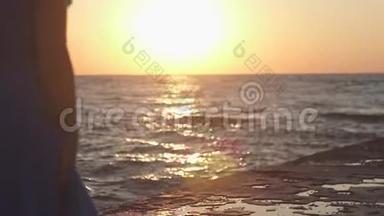 那个女孩在码头上的海面上迎接黎明.. 日出和日出背景下女孩的剪影