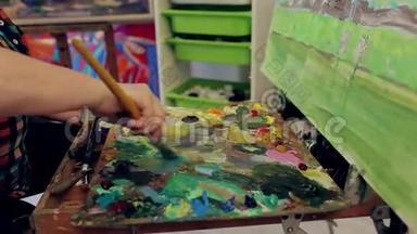 女艺术家把油画颜料混合在调色板上，在画室里画一幅<strong>风景画</strong>