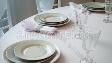 带有白色桌布的圆桌，餐盘，酒杯和餐巾纸