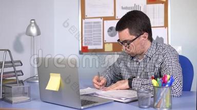 忙碌的人在工作场所填写纸质表格，看着笔记本电脑显示器