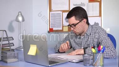 经理在工作场所填写纸质表格，查看笔记本电脑显示器