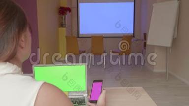看着笔记本电脑和智能手机屏幕的坐着女孩的后视图准备演示