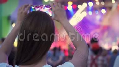 露天摇滚音乐会的人群聚会。 女人站着，手里拿着智能手机拍摄视频