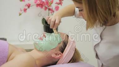 美容师在水疗沙<strong>龙</strong>里给躺着的女人戴上<strong>面具</strong>。