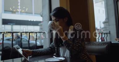 年轻女子坐在城市的咖啡馆里，用平板电脑看电影。 4k