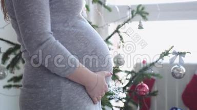 快乐的年轻家庭。 丈夫抱着他怀孕的妻子靠近窗户边美丽的<strong>装饰</strong>圣诞树。 快关门。 慢慢慢慢