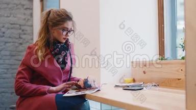 舒适的咖啡馆©一个€™的内部，迷人的欧洲女孩，穿着时尚的休闲服坐在窗边<strong>翻页</strong>