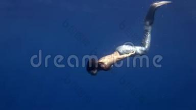 年轻女孩在红海的蓝色背景上模特水下美人鱼服装。