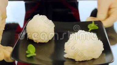 厨师把一盘寿司配料放在桌子上。 寿司、米饭和蔬菜的配料