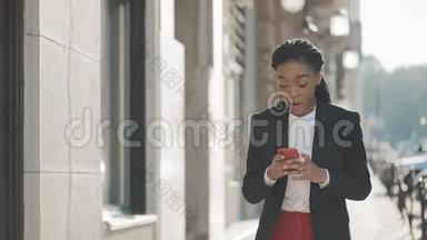 漂亮的女商人使用智能手机在<strong>商业</strong>中心附近的街道上行走。 黑色<strong>时尚</strong>。 可怕的家伙。
