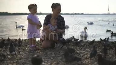 年轻的母亲带着她的小女儿在<strong>河边</strong>喂天鹅和小鸭子，小鸟在<strong>河边</strong>吃面包，穿着点缀的裙子