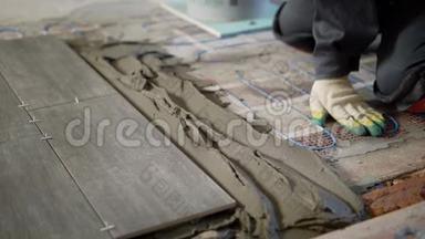 建筑工人双手戴手套，将水泥混合物放在砖地板上，在砖地板下面涂上胶水